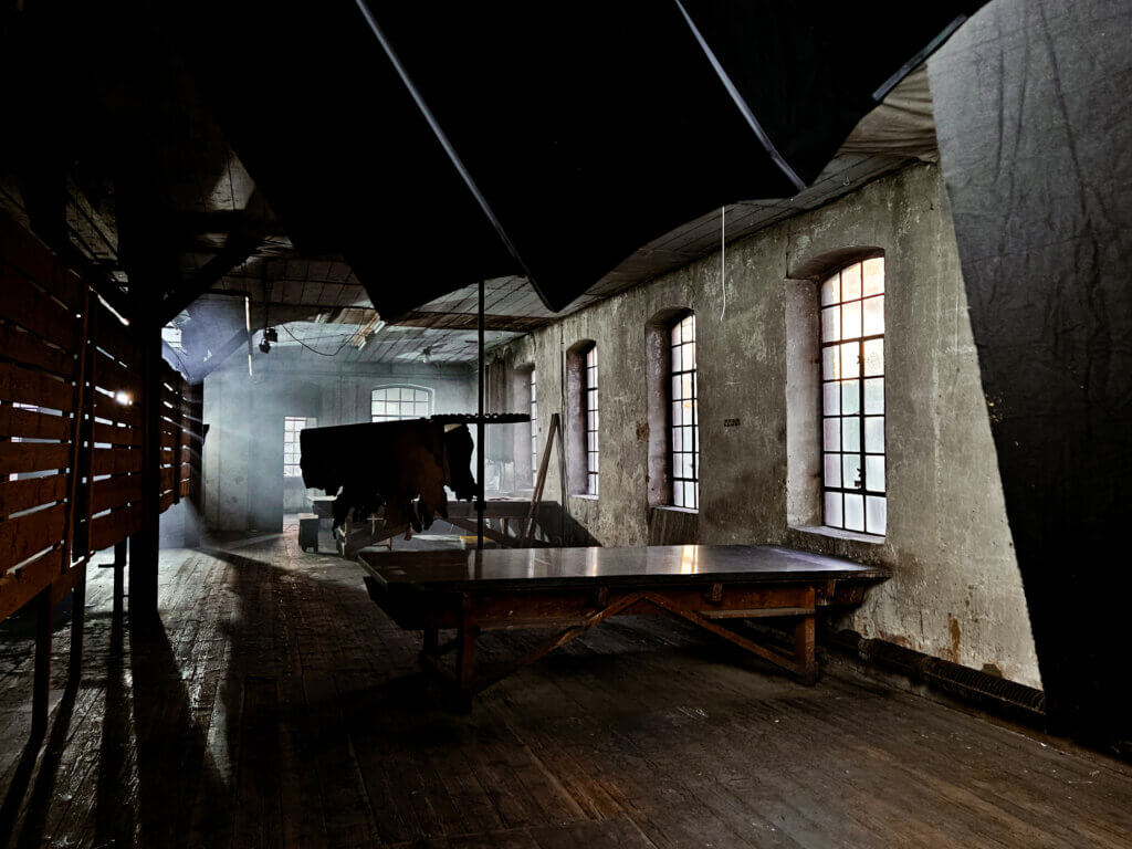 Lichtdurchflutete Industriehalle im Röhm mit alten Holzbalken, großen Fenstern und Nebeleffekten, vorbereitet als Set für die Musikvideoproduktion.